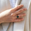 photo of a hand wearing the signet round in gold vermeil with a emerald in the ring finger